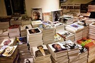 Huge stacks of diverse fashion and lifestyle magazines piled high in an indoor store setting.